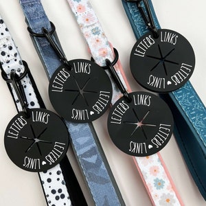 May include: Four dog leashes with different patterns, each with a black metal tag that says "LETTERS LINKS" in white lettering.