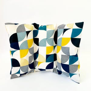 May include: Three decorative throw pillows with a geometric pattern of blue, yellow and black semi-circles on a white background.