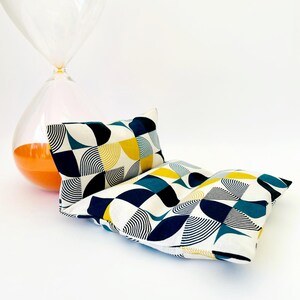 May include: Two rectangular cushions with a geometric pattern of blue, yellow and white circles and lines. The cushions are made of a soft, white fabric.