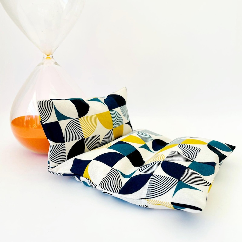 May include: Two rectangular cushions with a geometric pattern of blue, yellow and white circles and lines. The cushions are made of a soft, white fabric.