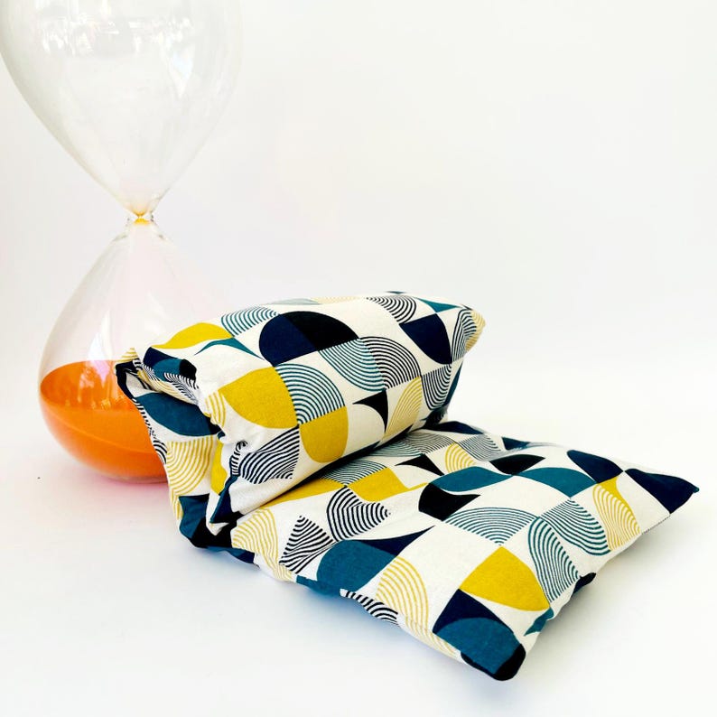 May include: Two rectangular cushions with a geometric pattern of yellow, blue and black circles and lines on a white background.