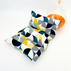 May include: A white, blue and yellow geometric patterned cushion with a matching smaller cushion. The cushions are made of fabric and have a modern design.