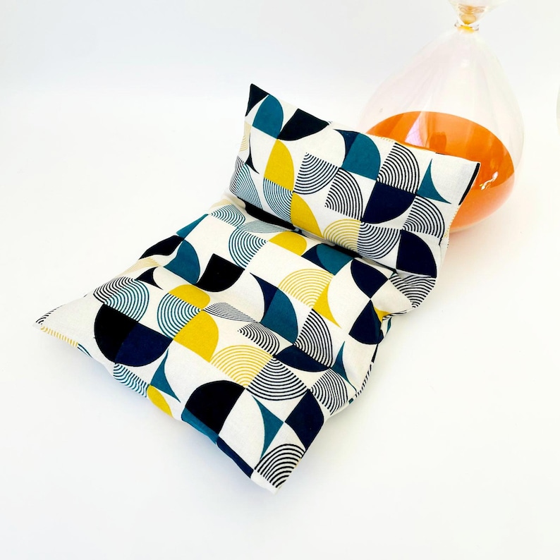 May include: A white, blue and yellow geometric patterned cushion with a matching smaller cushion. The cushions are made of fabric and have a modern design.
