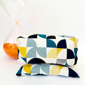 May include: Two rectangular cushions with a geometric pattern. The pattern features teal, yellow, black, and white circles and semi-circles.