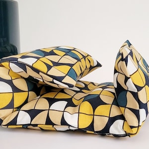 Peut inclure: Un ensemble de trois coussins décoratifs avec un motif géométrique dans des tons de jaune, blanc, noir et turquoise.