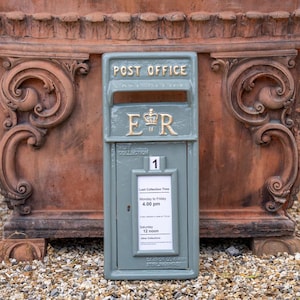 May include: A light green Post Office mailbox with gold lettering, including the royal cypher "ER". The mailbox displays collection times in a window. The words "Post Office" are at the top. The mailbox is made by Carron Company, Stirling, Scotland.