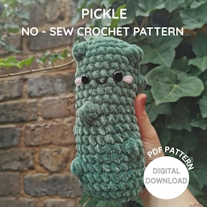 Peut inclure: Une peluche de cornichon au crochet vert sans couture, avec des yeux noirs et des joues roses. La peluche a un visage souriant et de petits bras et jambes. Le texte "PICKLE NO-SEW CROCHET PATTERN" est en haut. Un cercle blanc avec "PDF PATTERN DIGITAL DOWNLOAD" est en bas à droite.