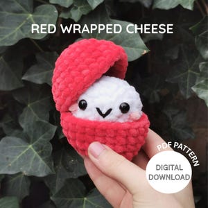 Puede incluir: Un juguete de queso envuelto en rojo, hecho a mano, con un centro de queso blanco sonriente. El texto "RED WRAPPED CHEESE" está en la parte superior. Un gráfico circular con "PDF PATTERN" y "DIGITAL DOWNLOAD" está en la parte inferior derecha.