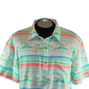 Pu&ograve; includere: Camicia a maniche corte con un design tropicale. La camicia presenta strisce orizzontali verdi, blu e corallo. Ha un colletto button-down e un motivo di palme e barche a vela.