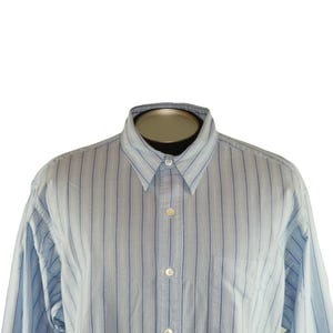 May include: Light blue button-down shirt with vertical stripes in a classic style. The shirt features a collared neckline, long sleeves, and a chest pocket. The stripes are a mix of light blue and white.