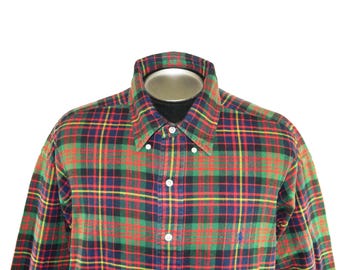 May include: A long-sleeved button-down shirt in a classic plaid pattern. The shirt features a combination of red, green, yellow, and blue colors. A small blue logo is visible on the left side of the shirt.