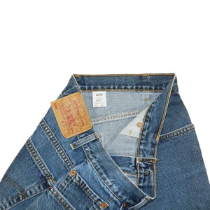 Könnte beinhalten: Blaue Jeans aus Denim mit einem beigen Lederaufnäher am Bund mit der Aufschrift Levi Strauss & Co. Quality Clothing 560 W 34 L 30. Das weiße Innenetikett zeigt 560 Loose Fit Tapered Leg W 34 L 30. Die Jeans hat orangefarbene Nähte.