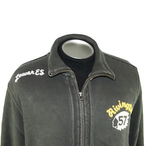 May include: Dark gray zip-up jacket with the words "Lower ES" embroidered in white on the left chest. The right chest features a yellow and white patch with the word "Rivington" and the number "57".