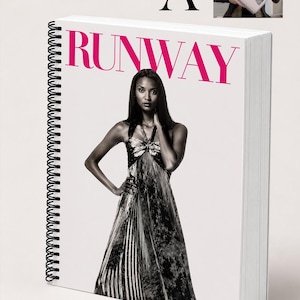 May include: A spiral-bound notebook with the word "RUNWAY" in pink letters. The notebook features a black and white image of a woman in a long dress. A smaller image in the corner shows a person holding the notebook.