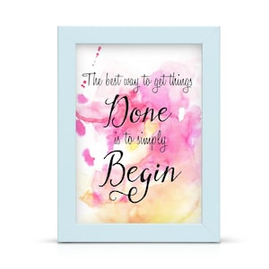 May include: A framed print with a pale blue border. The artwork features a watercolour background in shades of pink, yellow, and white. Black script reads, "The best way to get things Done is to simply Begin."