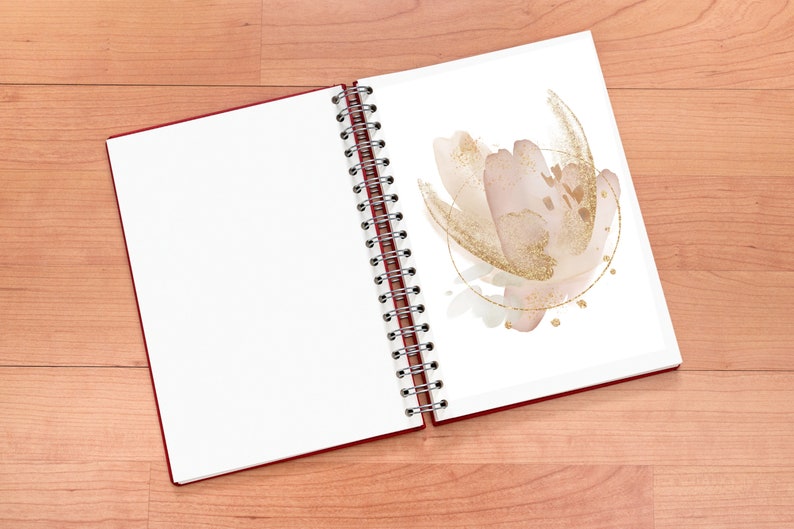 May include: Open spiral-bound notebook with a red cover. The right page features a watercolor floral design in blush pink and gold. The left page is blank. The notebook is on a light brown wooden surface.