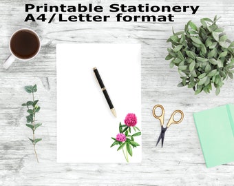 May include: Printable stationery in A4/Letter format with a white sheet of paper, a black pen, a pair of gold scissors, a green notebook, and a sprig of green leaves with pink flowers.