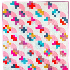 May include: A quilt featuring a repeating pattern of light pink semi-circles and multi-colored pixelated cross shapes on a white background. The design includes accents of red, teal, dark blue, yellow, and magenta, finished with a thin purple border.