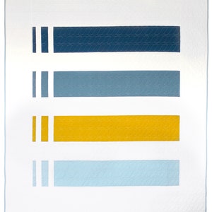 Peut inclure: Une courtepointe rectangulaire avec un fond blanc et quatre bandes horizontales en bleu marine, bleu clair et jaune. Chaque bande a un motif texturé. Des rayures blanches verticales sont sur le côté gauche de chaque bande. La courtepointe est bordée de blanc.