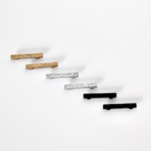 May include: Five different metal drawer pulls in various finishes. Two are gold, two are silver, and one is black.