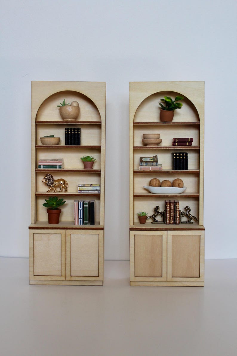 Two arched dollhouse bookshelves with miniature decor and accessories