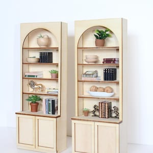 Two arched dollhouse bookshelves with miniature decor and accessories