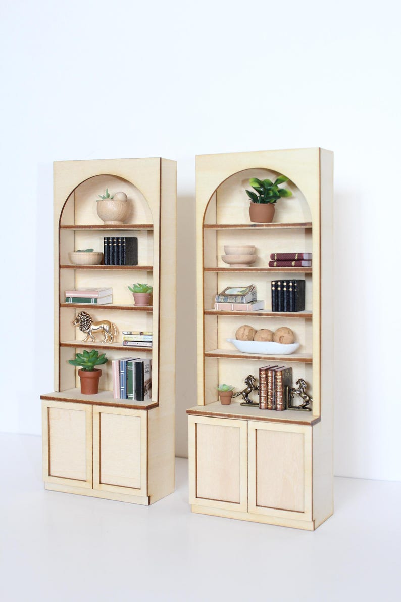 Two arched dollhouse bookshelves with miniature decor and accessories