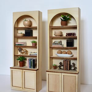 Two arched dollhouse bookshelves with miniature decor and accessories