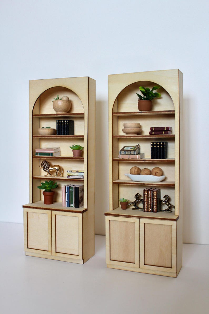 Two arched dollhouse bookshelves with miniature decor and accessories