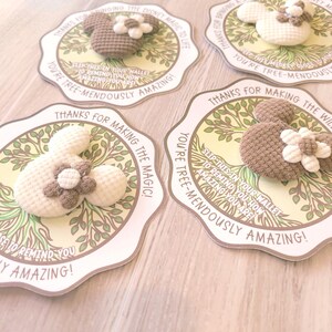 May include: Four handmade crochet Mickey Mouse-shaped cards with floral accents. Each card features a tree design and text that reads, "Thanks for making the magic!" and "You're tree-mendously amazing!"