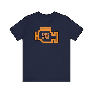 Puede incluir: Camiseta azul marino con un icono naranja de luz de control del motor y el texto "EVERY THING IS FINE".