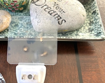 Op de afbeelding: Een witte stekkeradapter met de tekst "Follow Your Dreams" en "Go with the Flow" op twee decoratieve hartvormige stenen.