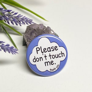May include: A blue button with a white cloud shape that says "Please don't touch me." with the words "thank you" in smaller text below the cloud.