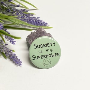 May include: A green button with the text "SOBRIETY is my SUPERPOWER" and a triangle symbol.