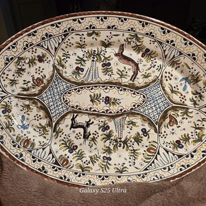 May include: Oval ceramic serving platter with a hand-painted design. The off-white surface features a brown rim and is decorated with floral and animal motifs, including deer and butterflies. The platter is divided into sections.