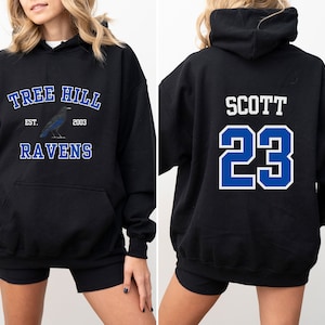 May include: Black hooded sweatshirt with a blue and white graphic on the front that says "Tree Hill Est. 2003 Ravens" and a blue and white graphic on the back that says "Scott 23".