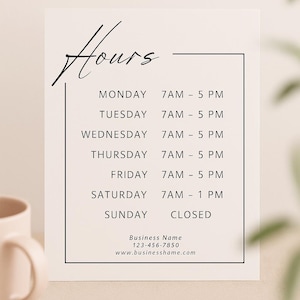 May include: A white business hours sign with black text. The sign displays the business hours for each day of the week, from 7 AM to 5 PM, except Saturday, which closes at 1 PM, and Sunday, which is closed. The sign also includes the business name, phone number, and website.