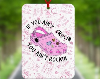 May include: Pink car air freshener with a pink and white cartoon clog shoe and the text "If you ain't crocin you ain't rockin".