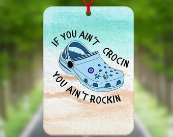 May include: A blue and white car air freshener with a cartoon image of a blue and white Croc shoe. The text on the air freshener reads "If you ain't crocin you ain't rockin".