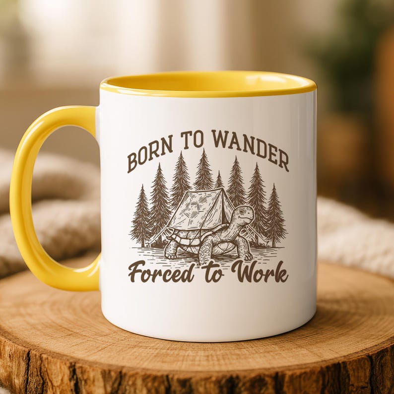 May include: White ceramic mug with a yellow handle and interior. The mug features a graphic of a turtle with a tent in front of a forest, and the text "Born to Wander Forced to Work" in a brown font.
