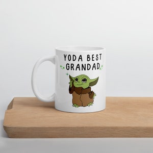 May include: White ceramic mug with a green cartoon character and the text "YODA BEST GRANDAD" in black.