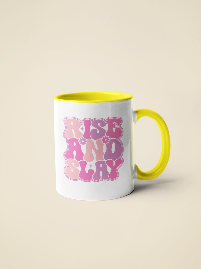May include: White ceramic mug with a yellow rim and handle. The mug features a pink and purple graphic that says "Rise and Slay" in a retro font.