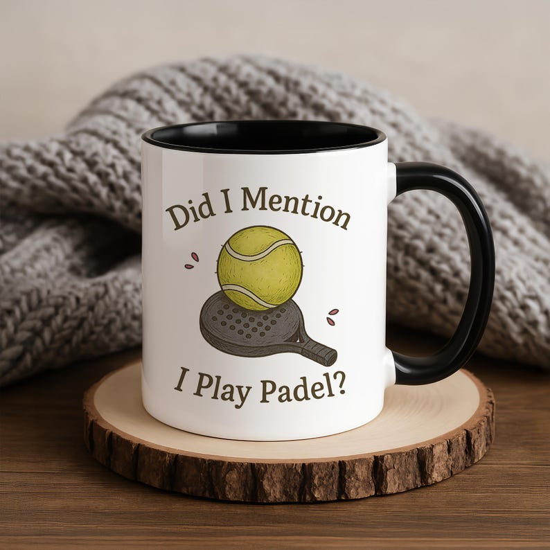 May include: White ceramic mug with a black interior and handle. The mug features the text "Did I Mention I Play Padel?" along with an illustration of a padel ball and racket. The mug sits on a wooden coaster.