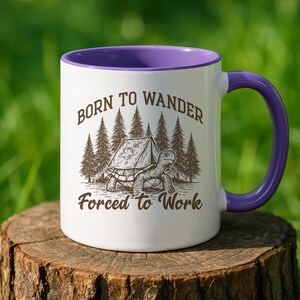 May include: White ceramic mug with a purple interior and handle. The mug features a graphic of a turtle with a tent in front of a forest, and the text "Born to Wander Forced to Work."