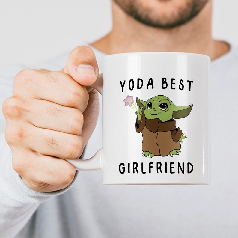 May include: White ceramic mug with a green cartoon character holding a flower. The text "Yoda Best Girlfriend" is printed on the mug.
