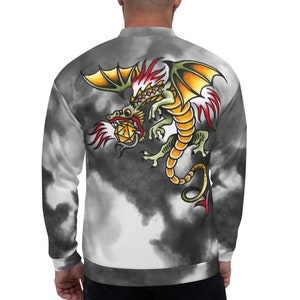 Op de afbeelding: Een zwart-witte tie-dye bomberjack met een kleurrijk draken-tattoo-ontwerp op de rug. De draak houdt een gele edelsteen vast in zijn klauwen.