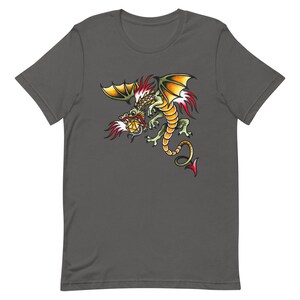 Op de afbeelding: Een donkergrijs T-shirt met een kleurrijke illustratie van een draak die een twintigzijdige dobbelsteen vasthoudt.