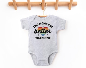 May include: A gray baby onesie with the text "Two Moms Are Better Than One" in black. A rainbow heart with stars is above the text.
