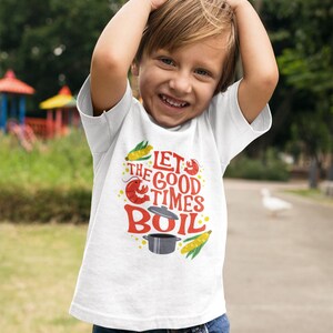May include: White t-shirt with a red, yellow, and black graphic design that says "Let the good times boil". The graphic includes a crawfish, corn on the cob, and a pot.