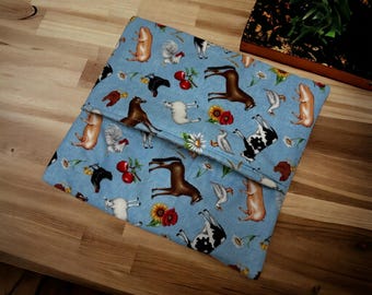 May include: A folded fabric pouch featuring a light blue background with a repeating pattern of farm animals including pigs, horses, cows, chickens, and geese, interspersed with red cherries, yellow sunflowers, and white daisy flowers.